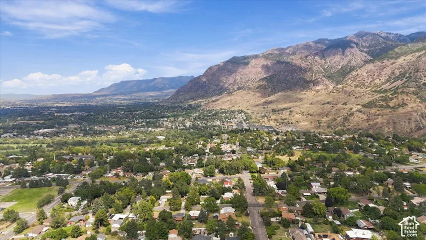 Expansive valley with a residential area, abundant mature trees, and mountainous terrain in the background