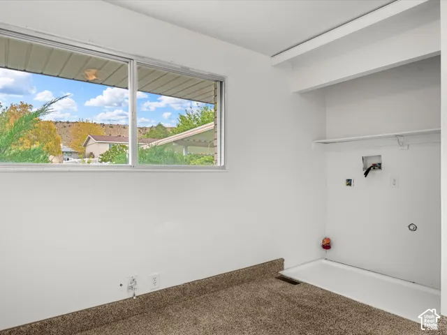 Large horizontal window, carpeted flooring, built-in shelving, and integrated utility connections