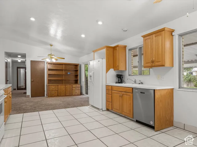 Spacious kitchen featuring wood-finish cabinetry, stainless steel dishwasher, tile flooring, and abundant counter space