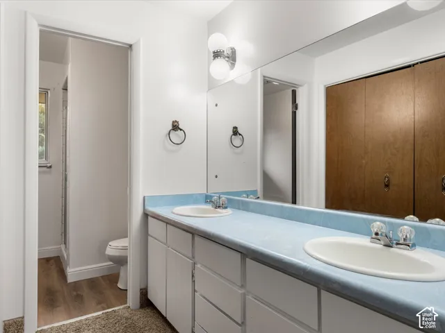 Double-sink vanity featuring a continuous countertop with integrated backsplash, white cabinetry, wall-to-wall mirror, and dual globe-style light fixtures