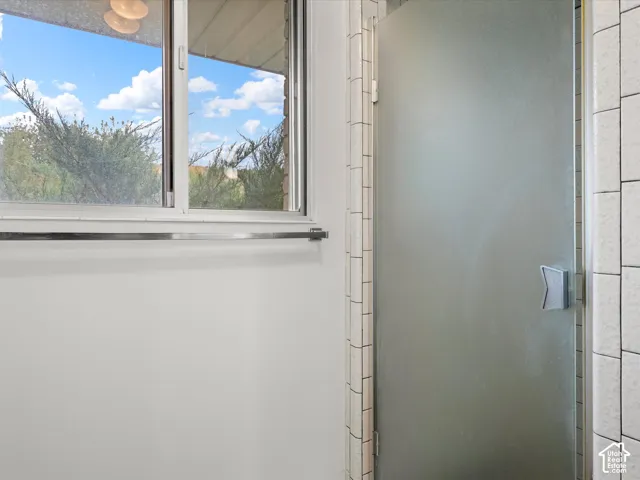 Horizontal sliding window with metal frame, glass shower enclosure with frosted finish, and vertical ceramic wall tile surround