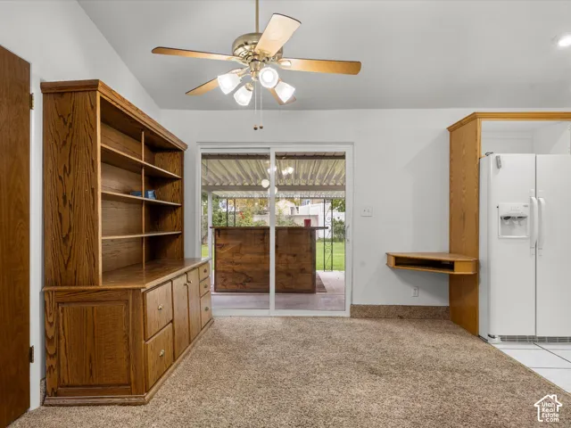 Built-in oak cabinetry featuring open shelving and lower storage drawers, integrated corner workspace, ceiling fan with light fixture, and glass sliding door providing exterior access