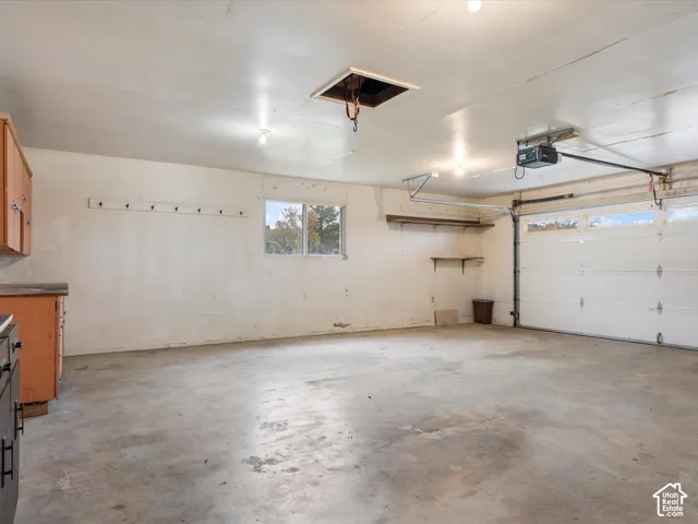 Two-car garage featuring a concrete floor, built-in wooden cabinetry, integrated wall-mounted shelving, and an automated overhead garage door