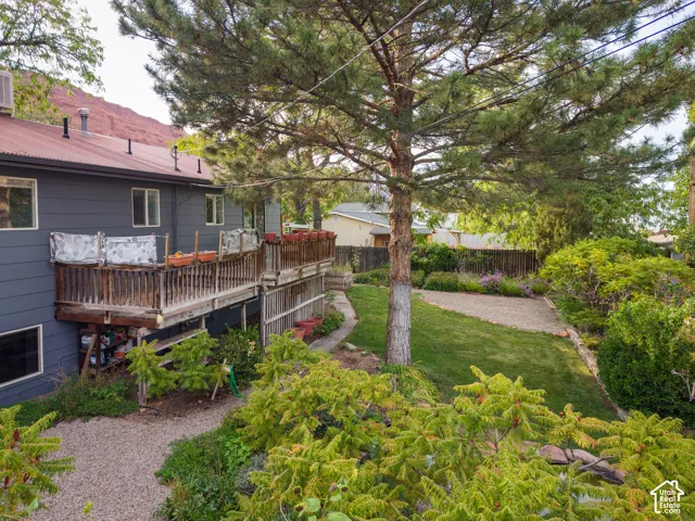 Two-story structure with a metal roof, an upper-level wood deck, and a gravel pathway