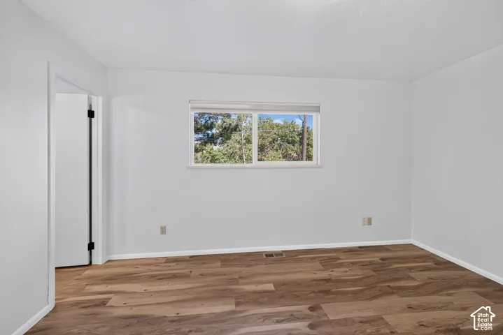 Wood-finish flooring with white baseboards, a white door frame, and a window