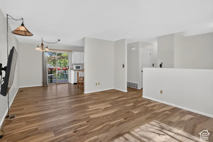 Wood-finish flooring, sliding glass door, white cabinetry, overhead lighting fixtures, and a half-wall partition