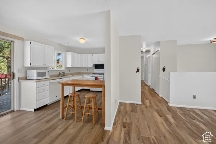Kitchen with white cabinetry, light-toned countertops, and wood-finish flooring