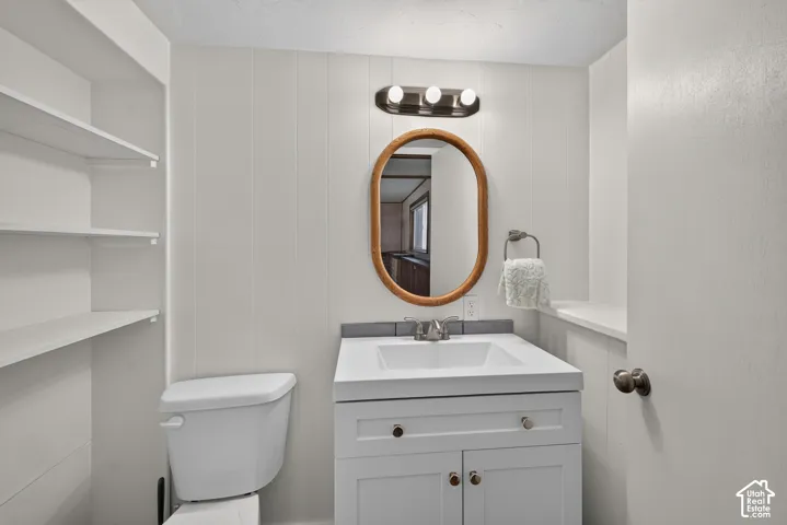 Bright bathroom featuring a gray vanity with dual cabinet doors and drawer storage, white ceramic sink, quartz countertop, oval wood-frame mirror, and chrome wall-mounted faucet