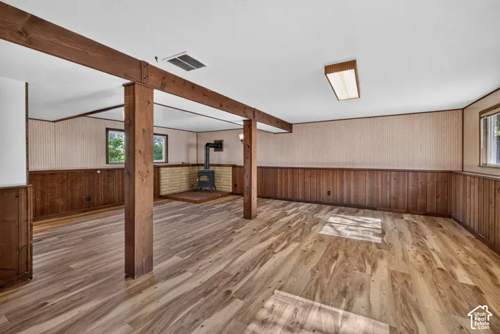 Wood-finish flooring, exposed wood beams, wood paneling, wood-burning stove, and brick hearth