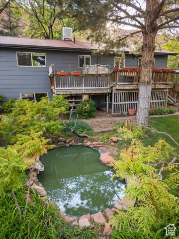 Multi-level rear deck, corrugated metal roof, rock-lined pond, surrounding mature trees, and landscaping
