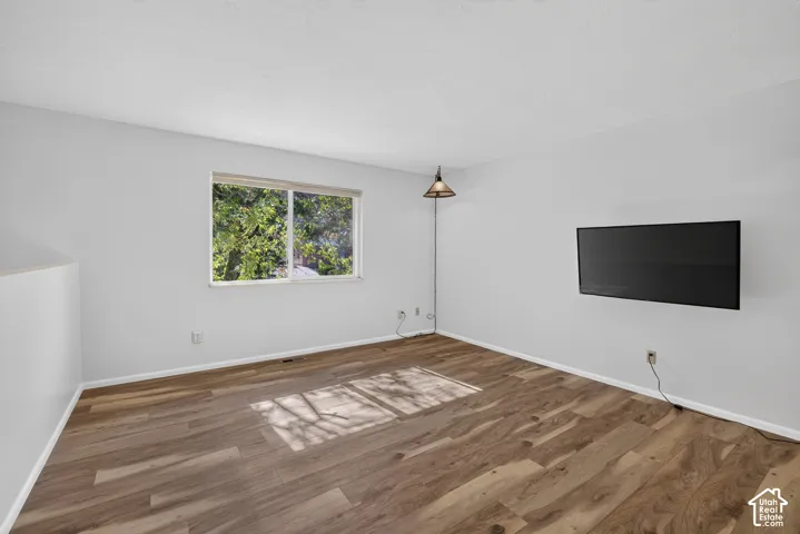 Wood-finish flooring, white walls, and a window with a white frame