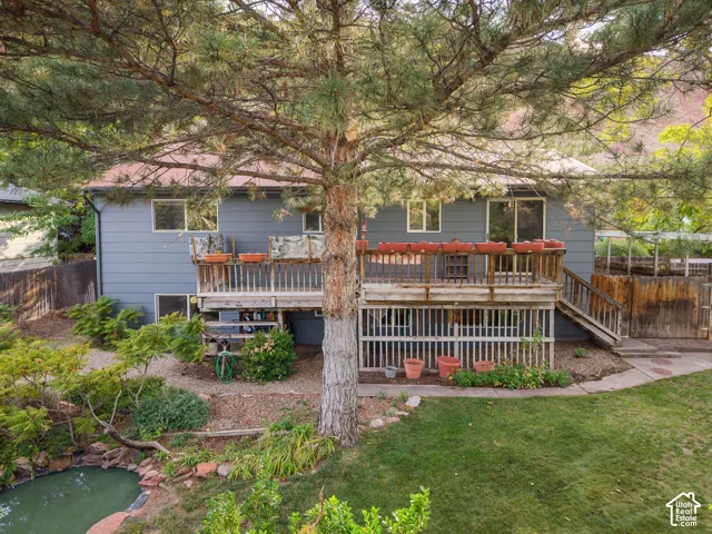 Expansive backyard featuring a large tree, a pond, and diverse landscaping