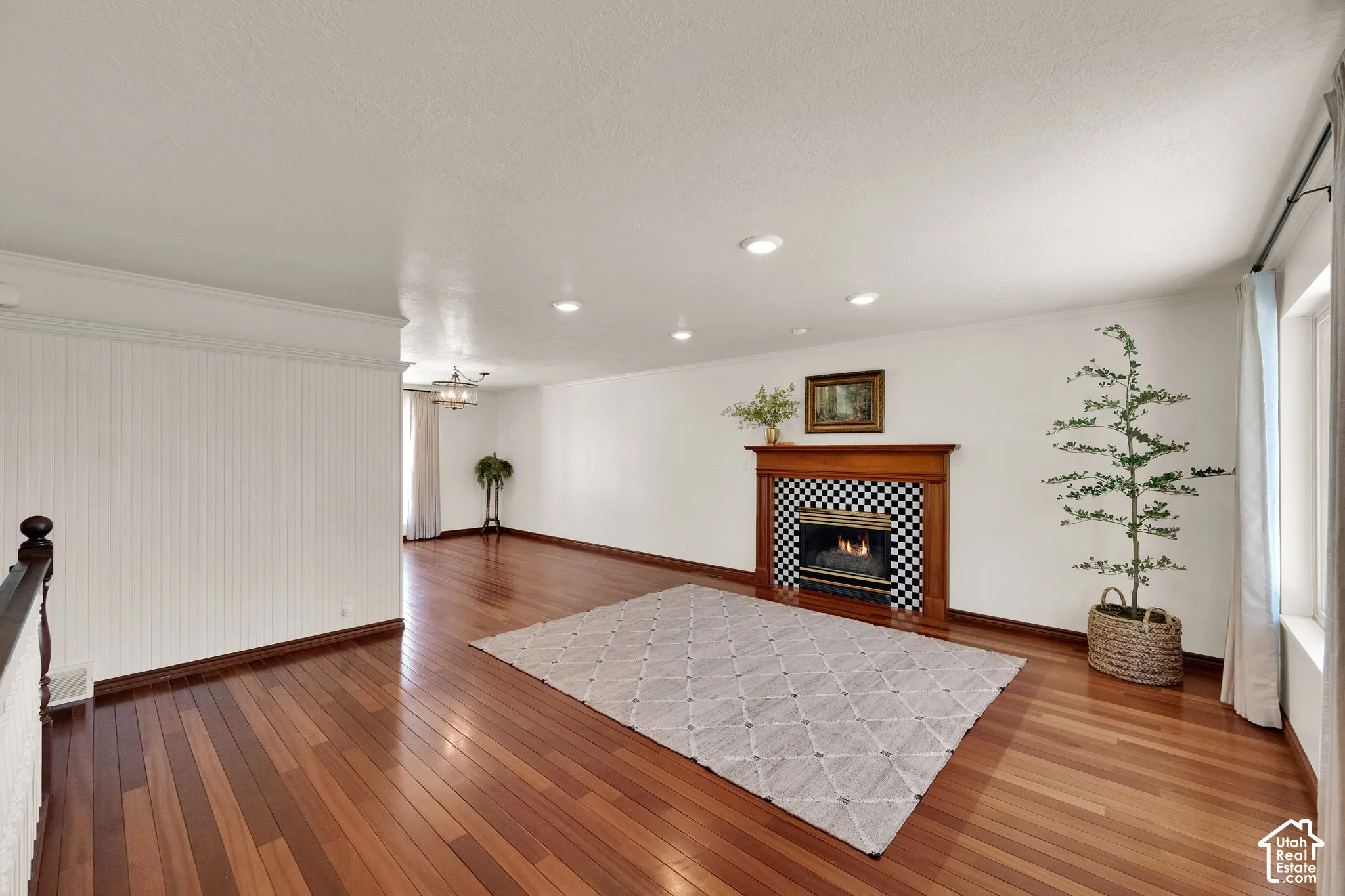 Rich wood-finish flooring, gas fireplace with wood mantel, recessed lighting, and a chandelier