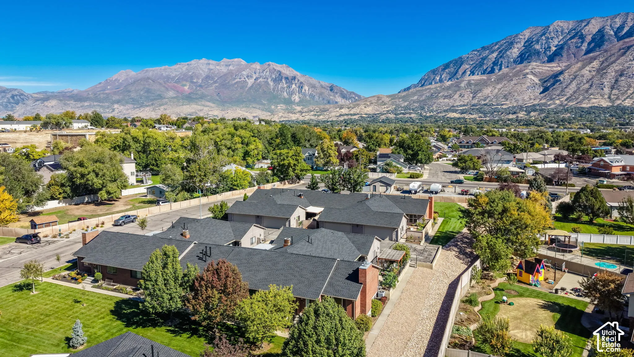 Property features multiple buildings with dark shingle roofs, surrounded by mature trees and green lawns