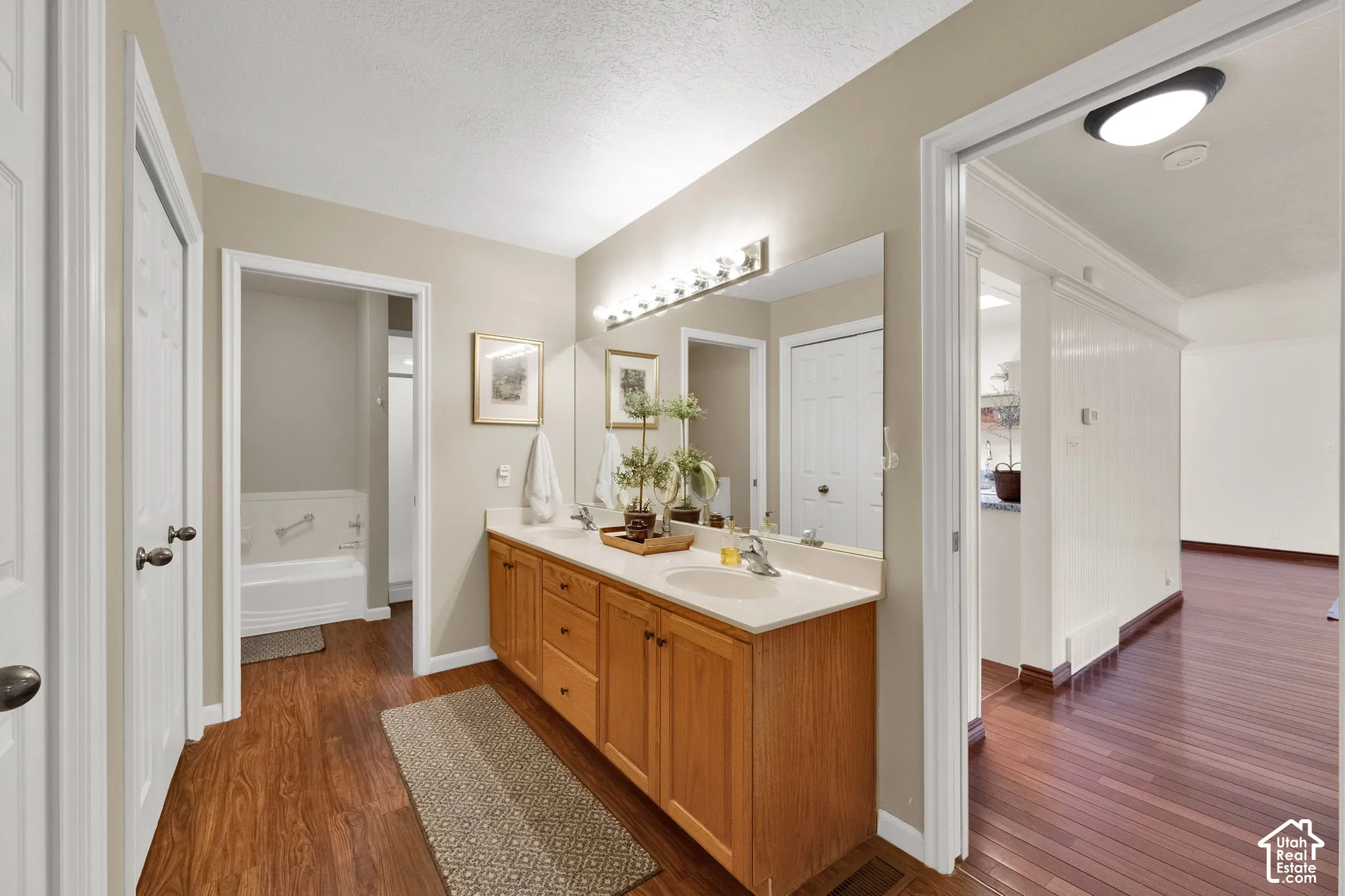 Dual vanity with integrated sinks, wood-finish cabinetry, and a large wall-mounted mirror