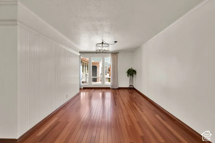 Hardwood flooring, wainscoting, crown molding, built-in lighting fixture, and floor-to-ceiling windows with views of the mountains