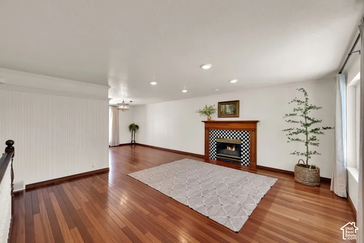 Rich wood-finish flooring, gas fireplace with wood mantel, recessed lighting, and a chandelier