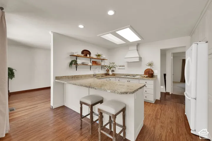 Kitchen featuring light toned cabinetry, granite countertops, wood-finish flooring, and recessed lighting