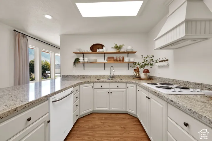 U-shaped kitchen with light toned cabinetry, granite countertops, wood-finish flooring, a white range, and a white dishwasher