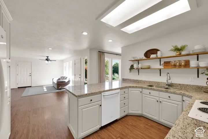 Open concept kitchen featuring an integrated dishwasher, wood-finish flooring, and granite countertops