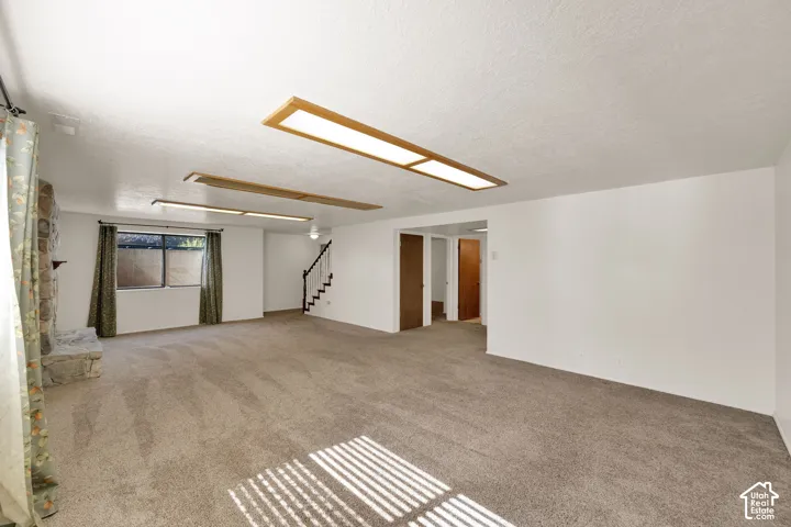 Spacious room featuring carpet flooring, a stone gas fireplace, and multiple windows