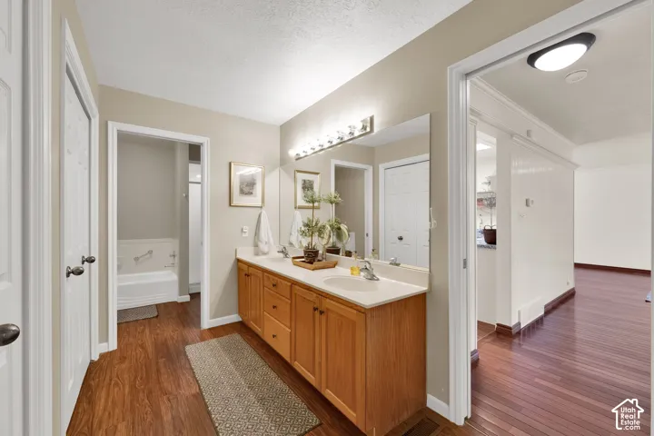 Dual vanity with integrated sinks, wood-finish cabinetry, and a large wall-mounted mirror