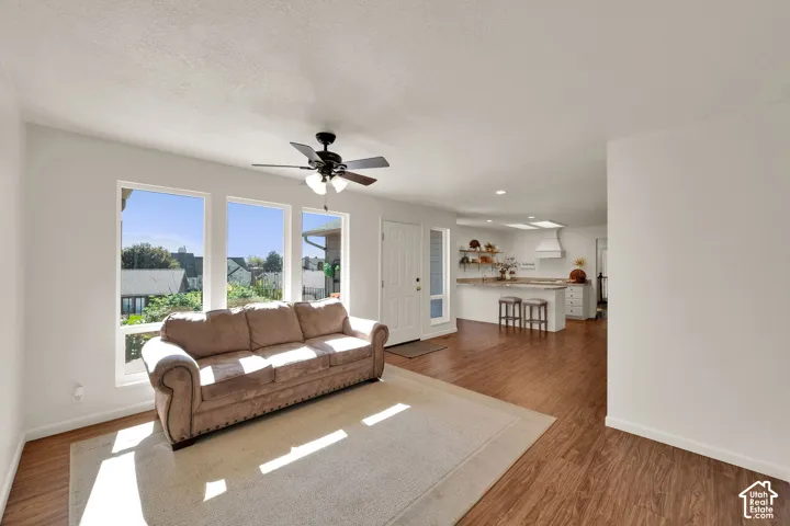 Open-concept living space featuring wood-finish flooring, multiple large windows, and a ceiling fan