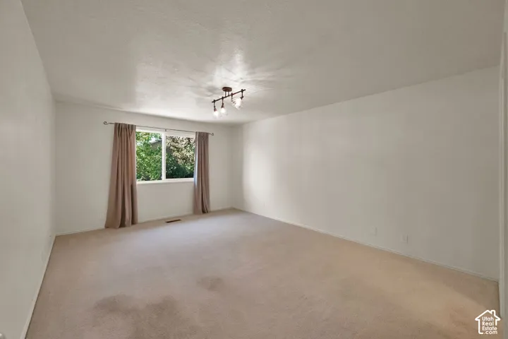 Spacious room, light-colored carpet, and a large window with natural light