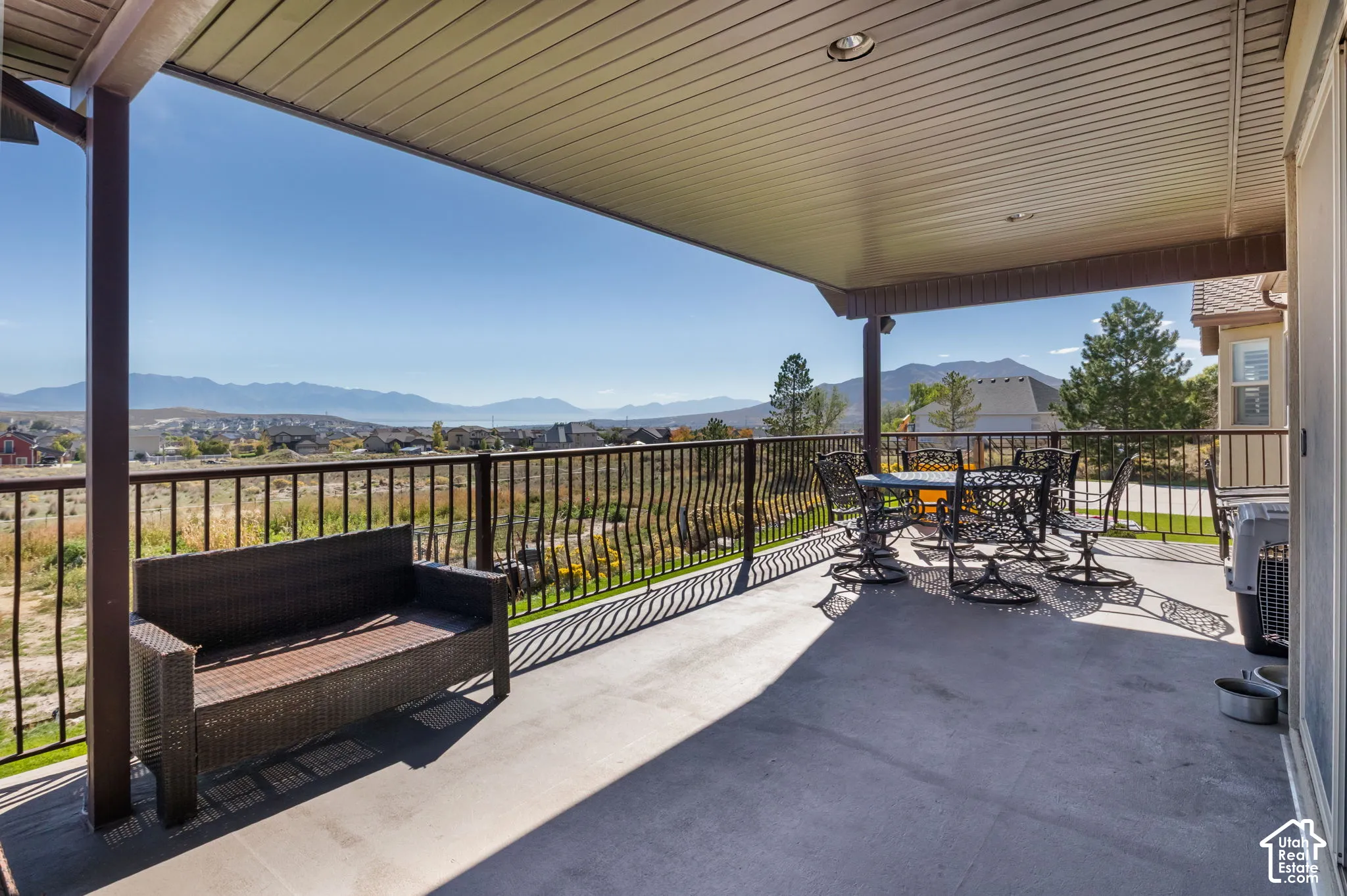 Covered concrete patio with a black metal railing and recessed lighting, offering expansive mountain scenery