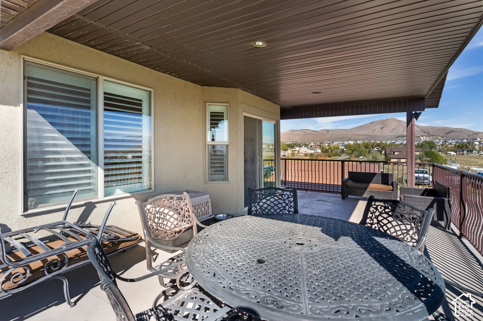 Covered outdoor patio with a mountain backdrop, featuring a dark brown slatted ceiling and recessed lighting