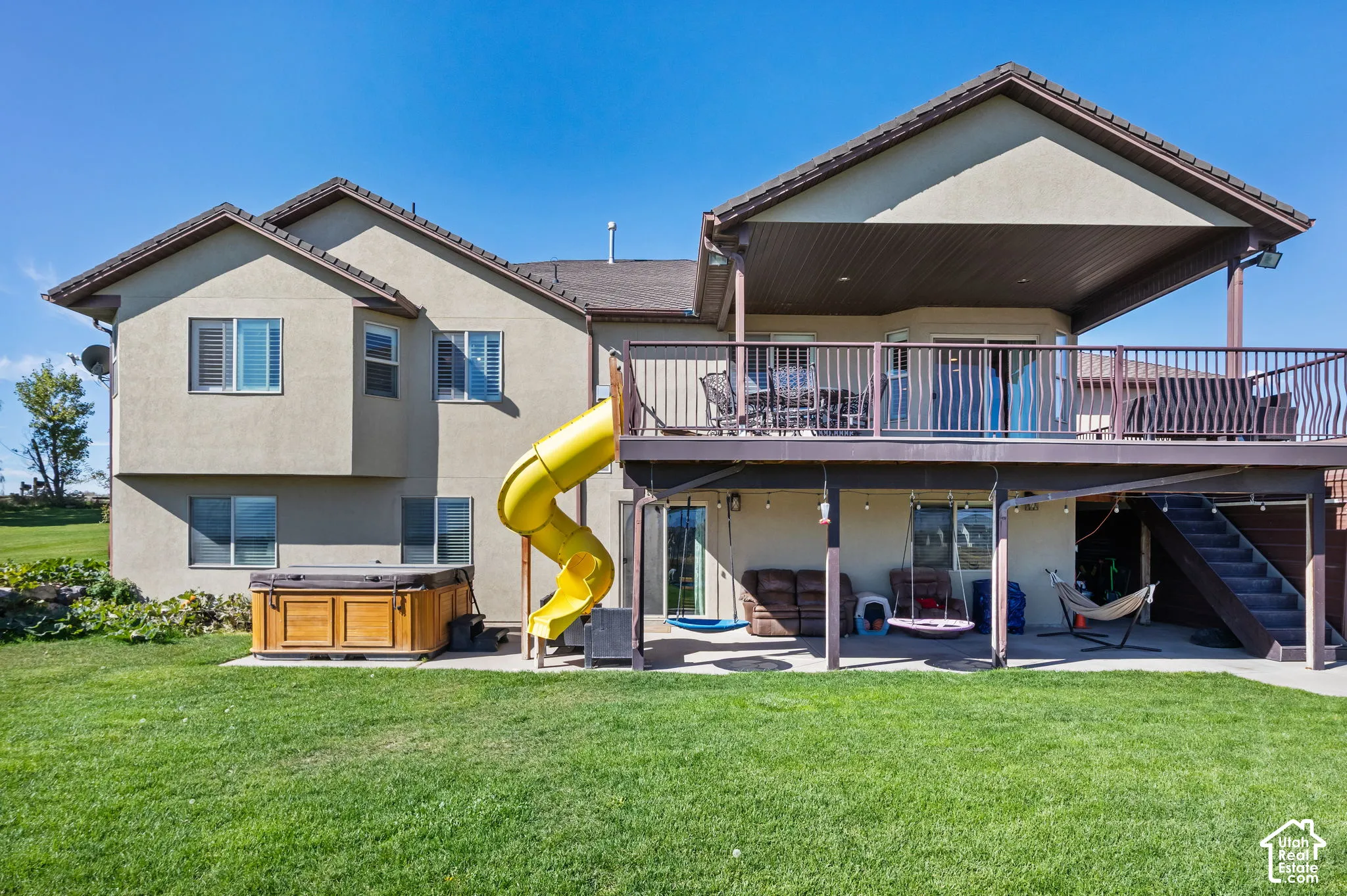Expansive green lawn with a lower-level concrete patio, complemented by a built-in outdoor spa