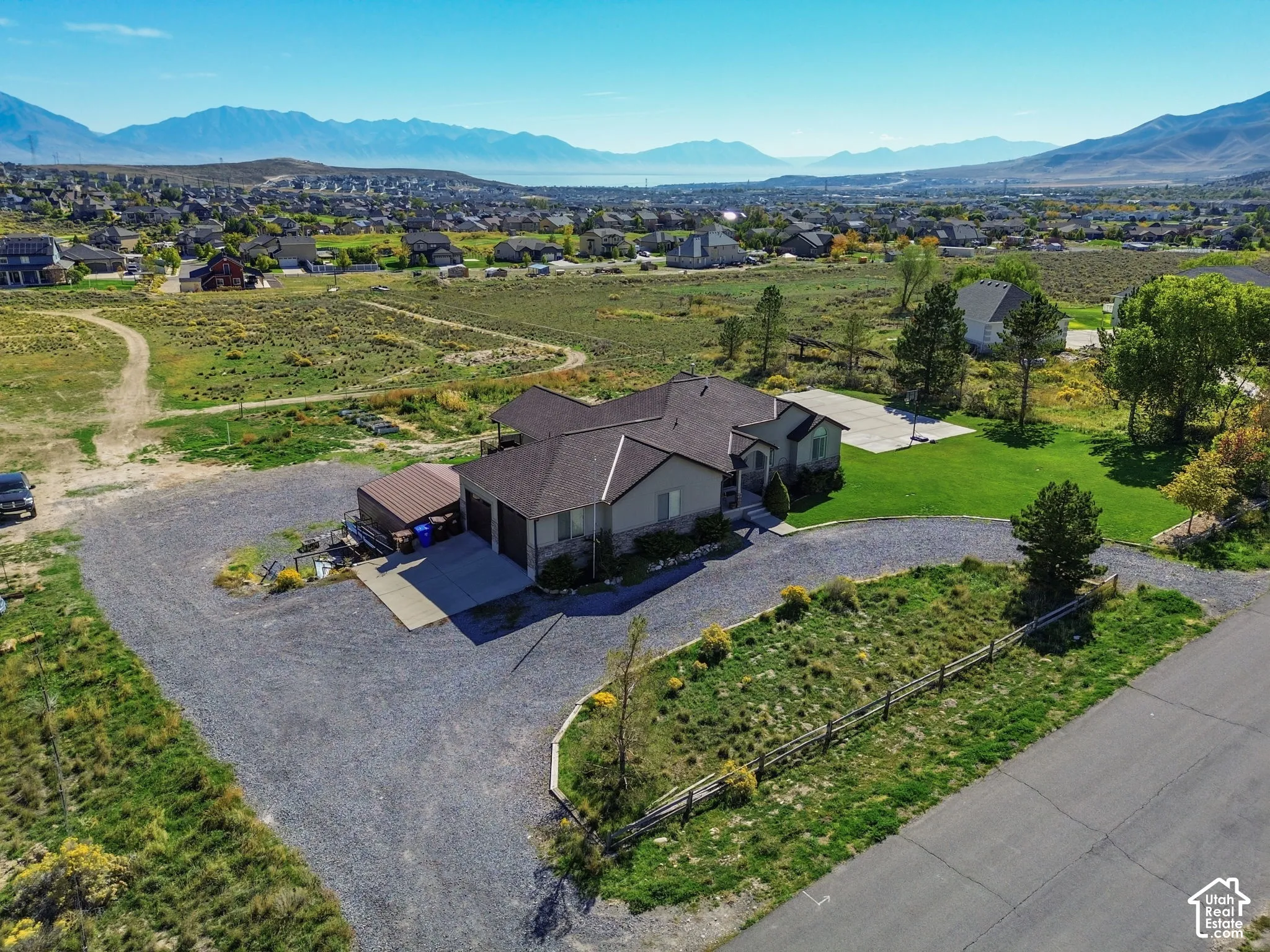 Single-story residence with a multi-car garage, gravel driveway, and a manicured lawn