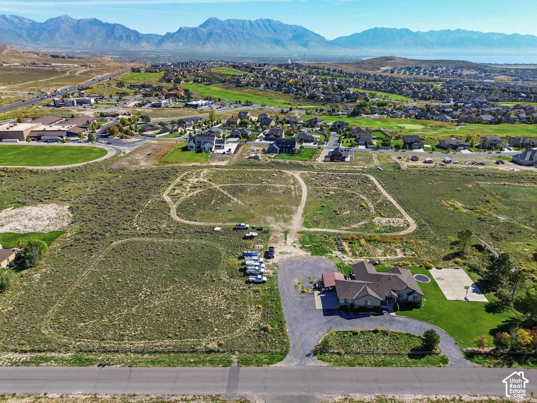 Expansive property featuring a single-story residence, asphalt driveway, basketball court, and manicured lawn