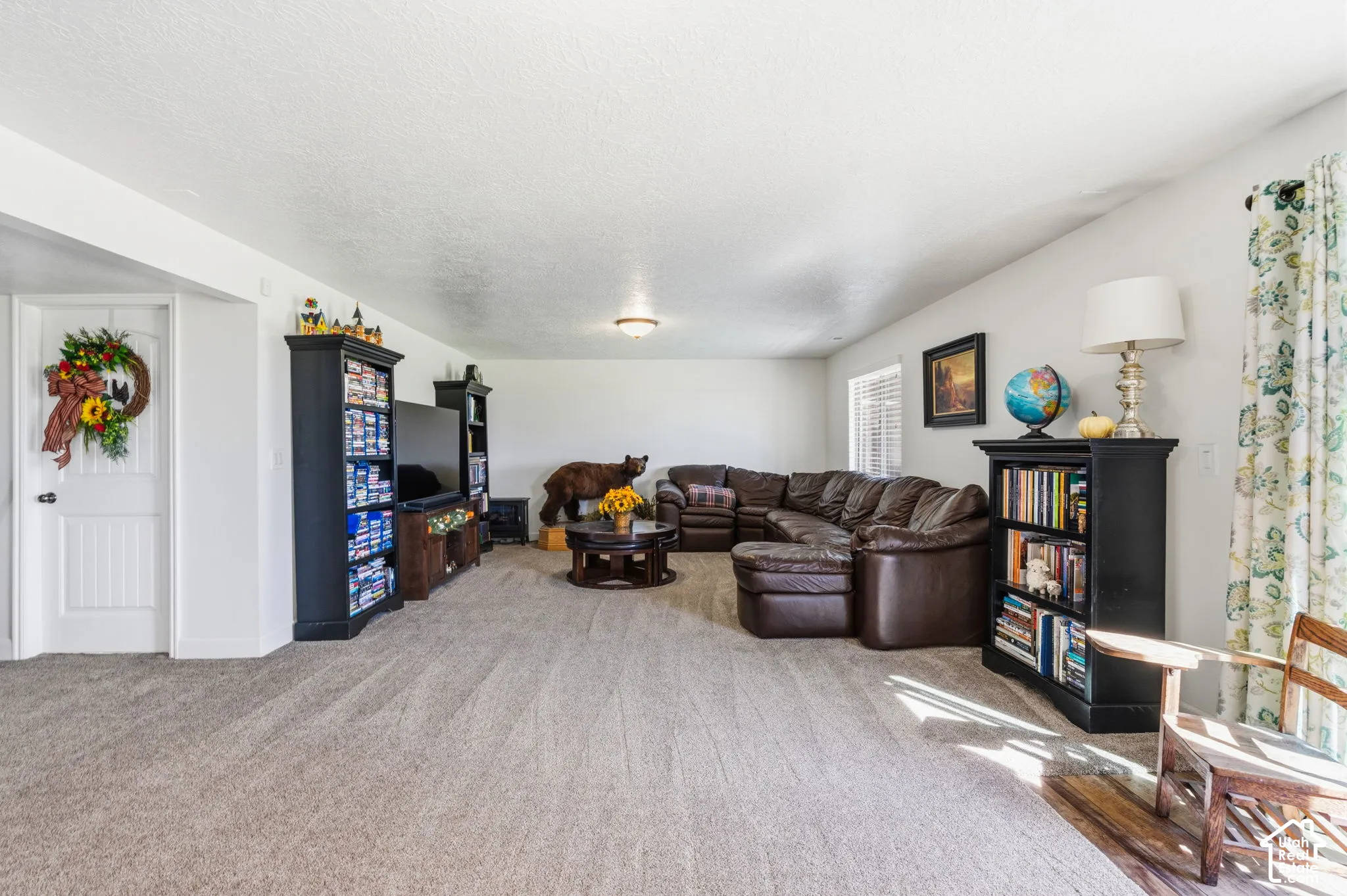 Recessed ceiling lighting, textured ceiling, white interior doors, window with blinds, and neutral carpeting