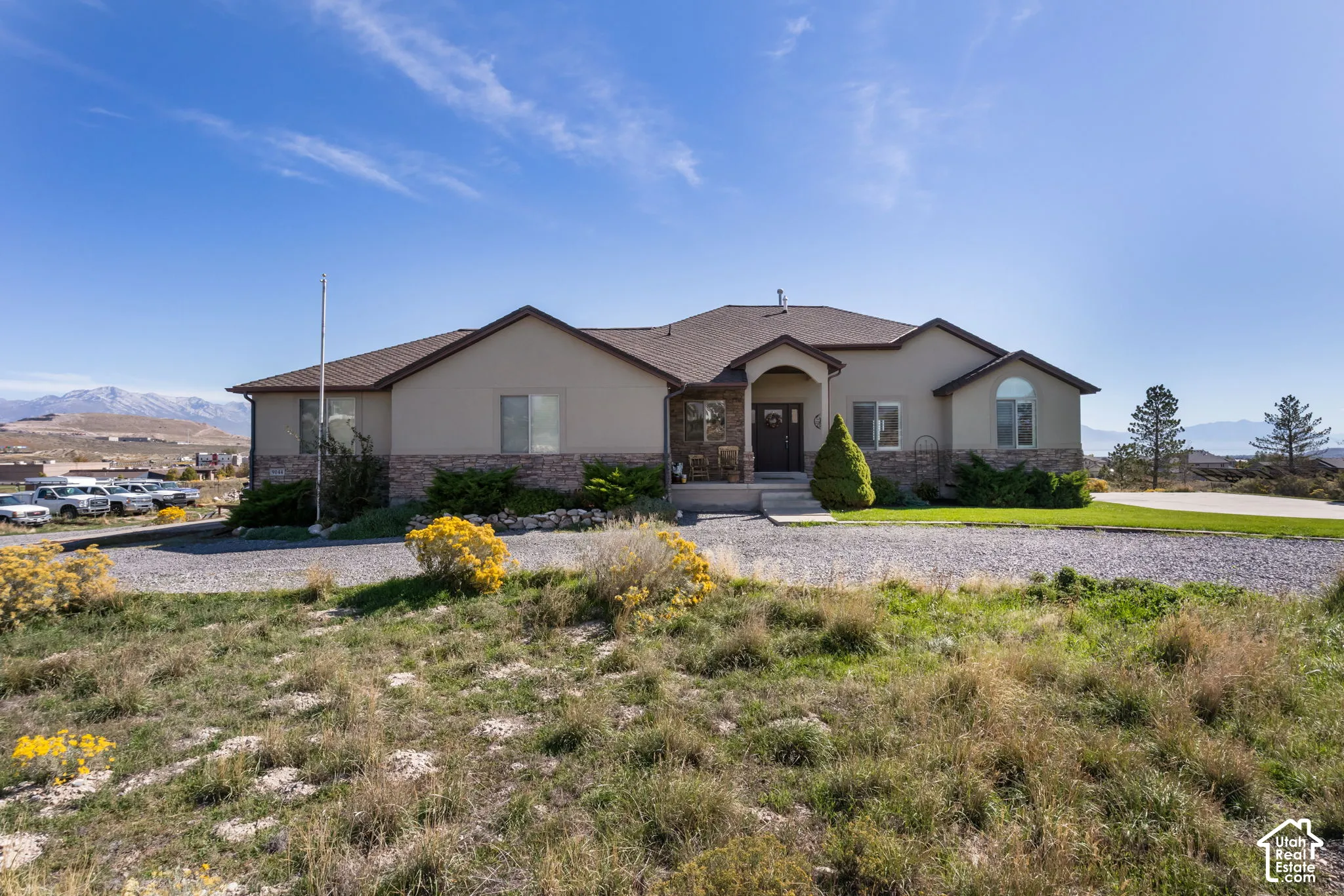 Stucco exterior with stone accenting, arched entry, and a wide gravel driveway