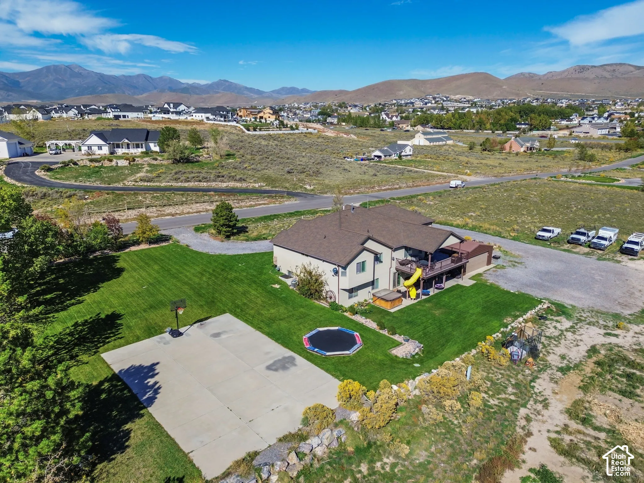 Expansive property with a large concrete sport court, lush green lawn, and a multi-level deck