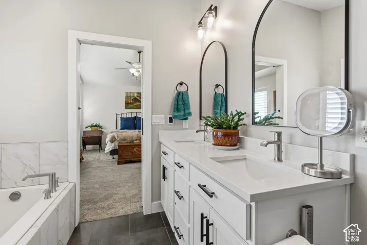Double vanity with integrated sinks, white cabinetry, dark hardware, and arched mirrors
