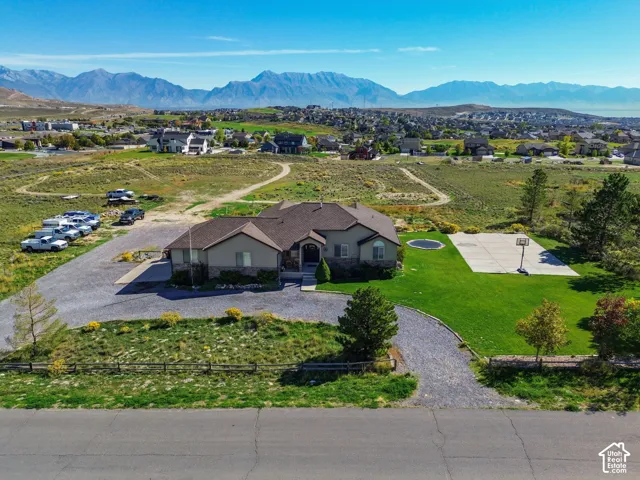 Ranch-style residence featuring a stone and stucco exterior, gravel driveway, and a manicured lawn
