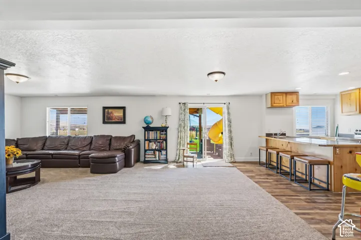 Open-concept living space featuring a carpeted area, wood-finish flooring, a kitchen island with seating, a sliding glass door, and recessed lighting