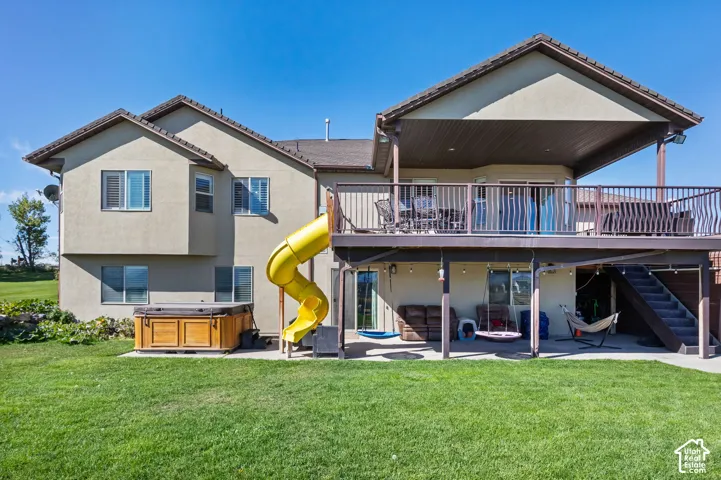 Expansive green lawn with a lower-level concrete patio, complemented by a built-in outdoor spa