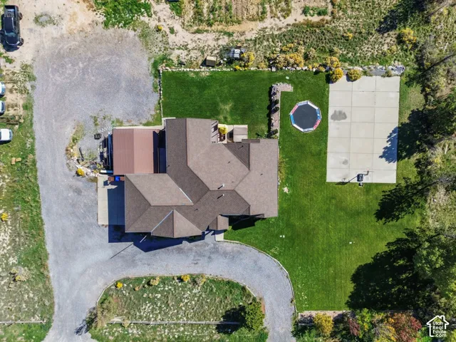 Expansive property featuring a multi-gabled roofline, concrete sports court, established green lawn, and gravel driveways