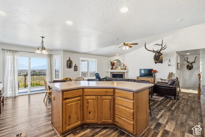 Spacious open-concept interior featuring vaulted ceilings, wood-finish flooring, and a kitchen island with built-in storage