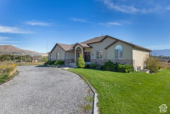 Stucco exterior with stone accenting, arched window, and gravel driveway
