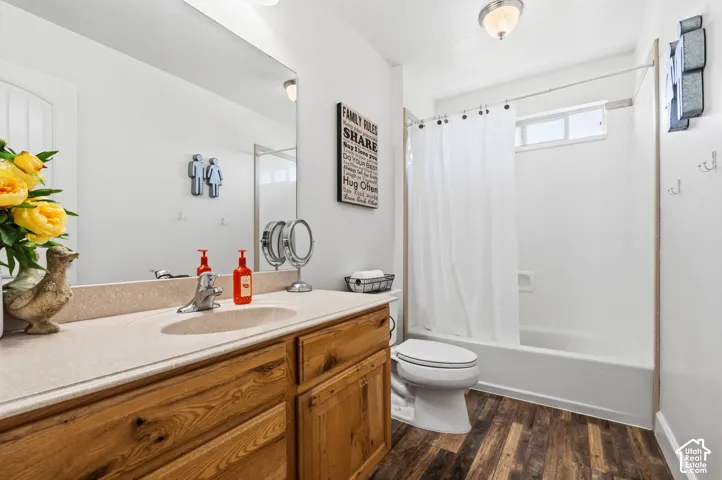 Wood-finish flooring with a white bathtub and shower combination
