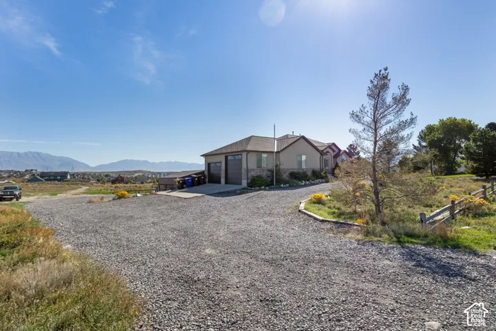 Gravel driveway leading to a residence with a two-car garage and stone accents