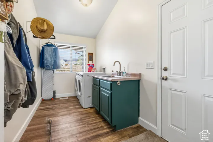 Laundry area with wood-finish flooring, built-in cabinetry, utility sink, and a window for natural light