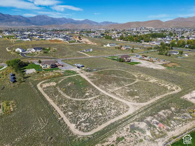 Expansive acreage featuring natural terrain, surrounding residential properties, and distant mountain ranges