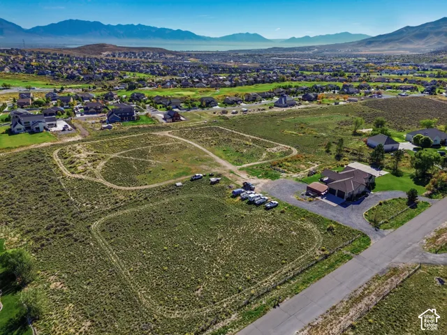 Expansive undeveloped lot with partial fencing, surrounded by established residential areas and distant mountains