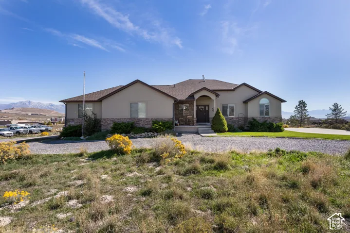 Stucco exterior with stone accenting, arched entry, and a wide gravel driveway