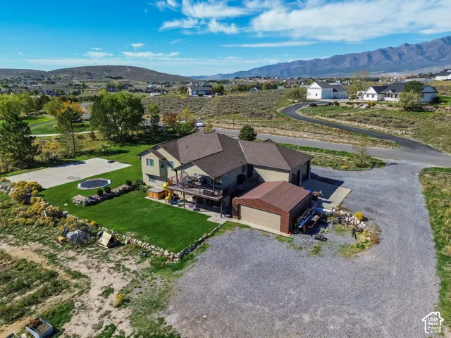 Expansive outdoor space featuring a well-maintained lawn, a paved court, and a multi-level deck
